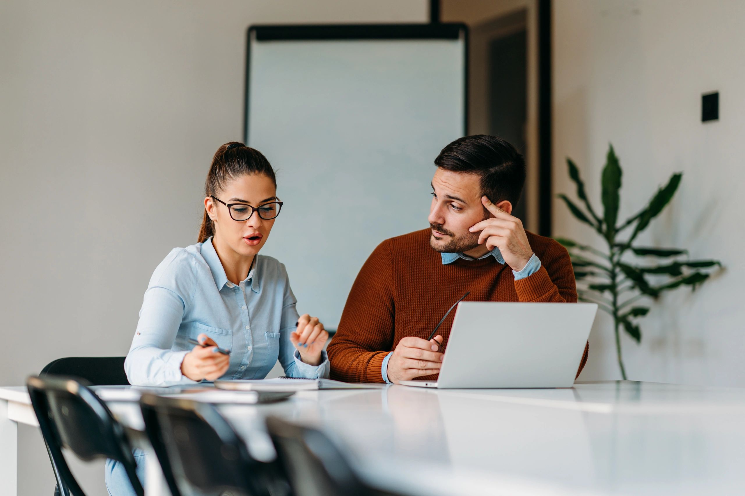 Two colleagues working together on a laptop and discussing a project